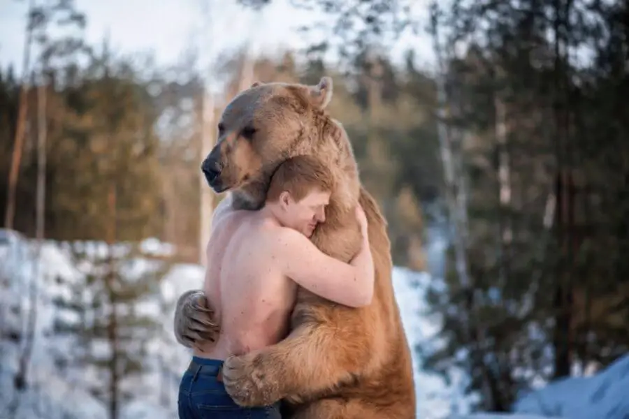 el hombre abraza a un oso en el bosque