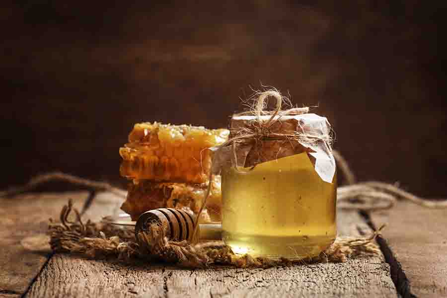Tarro de miel y panal, fondo de mesa de cocina de madera vintage